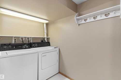 Dedicated laundry area featuring white appliances, upper storage shelf, and wall-mounted coat rack - 5501 48 Avenue, Wetaskiwin, AB 