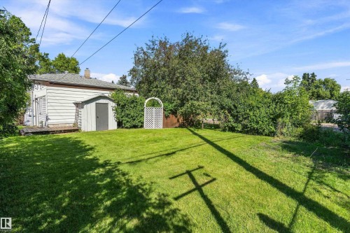 Expansive grassy lawn with a storage shed, a white lattice arch, and mature trees - 5501 48 Avenue, Wetaskiwin, AB 