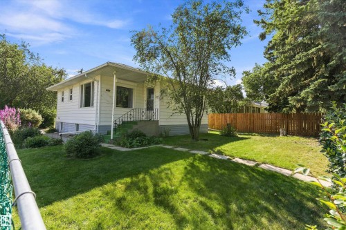 White siding exterior, covered front porch, wrought iron porch railing, established lawn, wood privacy fence - 5501 48 Avenue, Wetaskiwin, AB 