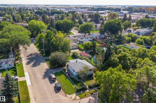 Aerial view showcasing a substantial corner-lot property with mature landscaping, manicured lawn, and established tree canopy - 5501 48 Avenue, Wetaskiwin, AB 
