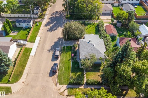 Corner lot property featuring a grey shingle roof, mature landscaping, and an adjacent paved street - 5501 48 Avenue, Wetaskiwin, AB 