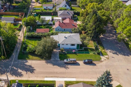Residential property featuring a light-colored exterior, an asphalt shingle roof, and a front yard with mature trees - 5501 48 Avenue, Wetaskiwin, AB 