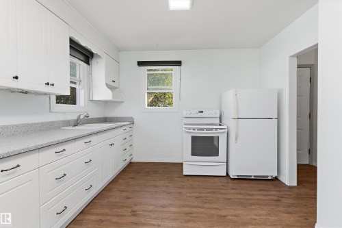 Bright, open kitchen featuring white cabinetry with brushed-nickel hardware, granite-style countertops, white tile backsplash, and stainless steel appliances including a gas range and refrigerator - 5501 48 Avenue, Wetaskiwin, AB 