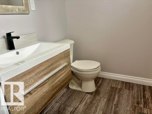 Wood-finish vanity with an integrated sink and matte black faucet - 5133 45A Avenue, Vegreville, AB 
