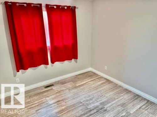 Window with red drapes, light-colored walls, and wood-finish flooring - 5133 45A Avenue, Vegreville, AB 
