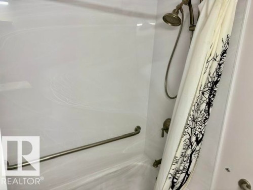 Shower with a handheld showerhead, wall-mounted faucet, and a grab bar - 5133 45A Avenue, Vegreville, AB 