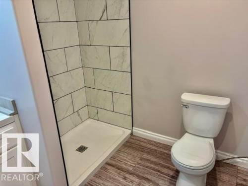 Shower enclosure with subway tile surround, white shower base, and wood-finish flooring - 5133 45A Avenue, Vegreville, AB 