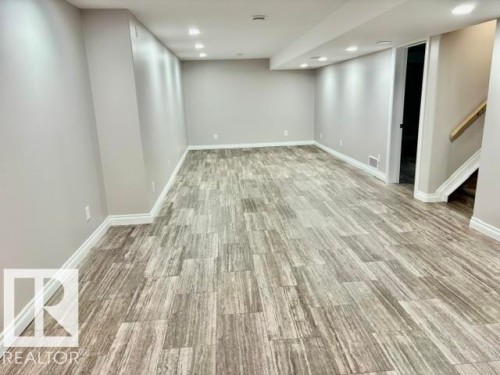Spacious room featuring modern wood-finish flooring, recessed ceiling lighting, and neutral wall paint - 5133 45A Avenue, Vegreville, AB 