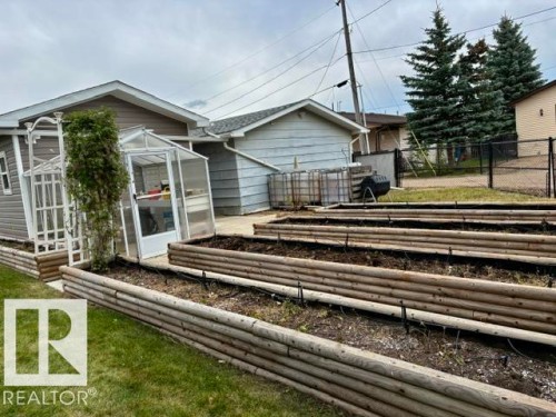 Multiple raised garden beds, a dedicated greenhouse structure, and a garden trellis - 5133 45A Avenue, Vegreville, AB 