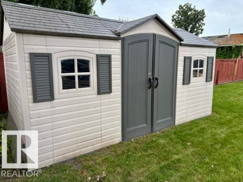 Exterior storage shed featuring a gabled roof, grey shingle-style roofing, and double entry doors - 5133 45A Avenue, Vegreville, AB 