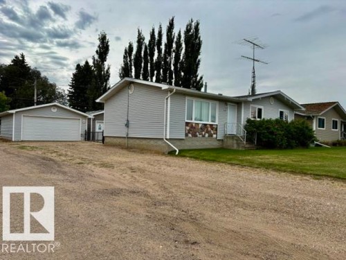 Siding exterior with stone accent detailing, attached garage, and gravel driveway - 5133 45A Avenue, Vegreville, AB 