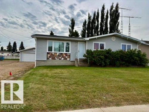 Siding exterior with stone accents, mature front landscaping, and a detached garage - 5133 45A Avenue, Vegreville, AB 