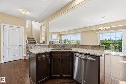Kitchen island featuring granite countertops, an undermount sink with a gooseneck faucet, dark wood cabinetry, and a stainless steel dishwasher - 