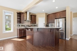 Spacious kitchen featuring rich wood cabinetry, stainless steel appliances, a large island with an integrated sink, tiled backsplash, and recessed lighting - 