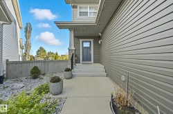 Grey siding exterior with a covered porch featuring a white column and stone veneer accent - 