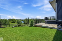 Expansive green lawn with a wooden deck featuring black metal railings - 