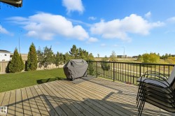 Expansive wooden deck with black metal railings, overlooking a grassy area and distant natural landscape - 