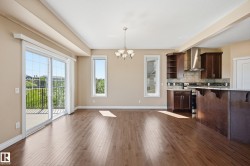 Open concept living area with wood-finish flooring, a contemporary chandelier, and a sliding glass door leading to an outdoor deck - 