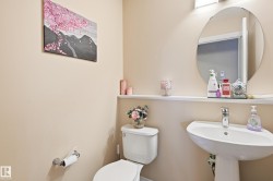Pedestal sink with chrome faucet, circular wall-mounted mirror, and wall-mounted light fixture - 
