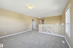 Carpeted bonus room featuring a balustrade railing, a window with white trim, and a flush-mount ceiling light - 