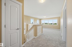 Spacious upper-level landing featuring light-toned carpeting, ample natural light from multiple windows, and a white balustrade - 