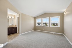 Spacious room featuring vaulted ceilings, three large windows, and plush grey carpeting - 
