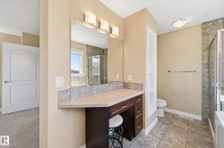 Integrated vanity with dark wood-finish cabinetry, a neutral countertop, and a tiled backsplash - 