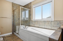 Bathroom featuring a built-in tub, tiled surround, and separate glass-enclosed shower - 