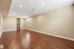 Spacious room featuring wood-finish flooring, recessed lighting, built-in shelving, and neutral wall tones - 