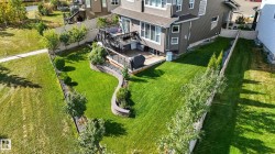 Spacious backyard featuring a multi-level deck, stone retaining walls, and established perimeter plantings - 