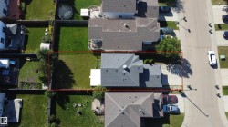 Gabled roofline, light gray shingle roofing, paved driveway, mature trees, manicured lawn - 