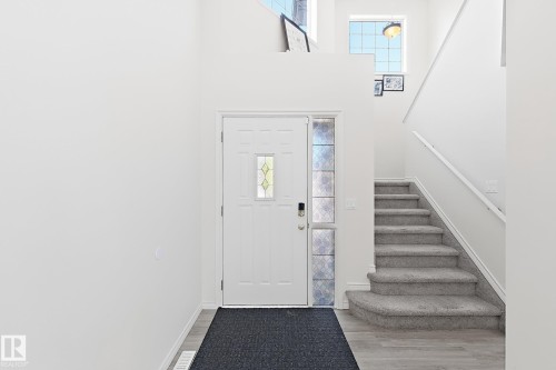 Entryway featuring a white paneled door with decorative glass inserts, a full-height decorative glass sidelight, and wood-finish flooring - 3525 22 St Nw, Edmonton, AB 