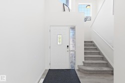 Entryway featuring a white paneled door with decorative glass inserts, a full-height decorative glass sidelight, and wood-finish flooring - 
