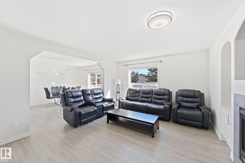 Spacious living area featuring light wood-finish flooring and a contemporary flush-mount ceiling light - 3525 22 St Nw, Edmonton, AB 
