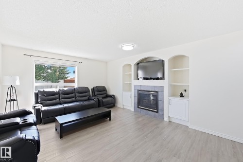 Recessed fireplace with tile surround, built-in shelving, white walls, and wood-finish flooring - 3525 22 St Nw, Edmonton, AB 
