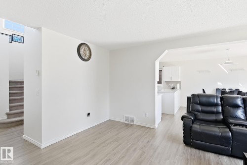 Light wood-finish flooring, white walls, and a staircase with neutral carpeting - 3525 22 St Nw, Edmonton, AB 