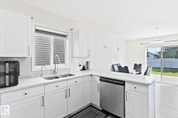 White kitchen cabinetry with stainless steel appliances, white countertops, and a tile backsplash - 