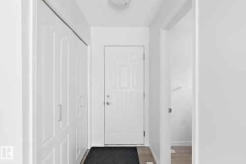 Entryway featuring a paneled door, wood-finish flooring, and built-in bi-fold closet doors with brushed nickel hardware - 3525 22 St Nw, Edmonton, AB 