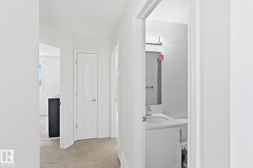 Bathroom featuring a single vanity with an integrated sink, polished chrome faucet, and decorative tiled wall - 3525 22 St Nw, Edmonton, AB 