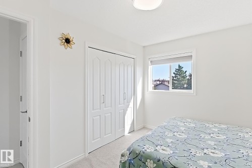Bright room featuring a window with a roller blind, carpeted flooring, a flush-mount ceiling light, and bi-fold closet doors - 3525 22 St Nw, Edmonton, AB 