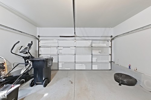 Concrete flooring with a white-painted garage door and walls - 3525 22 St Nw, Edmonton, AB 