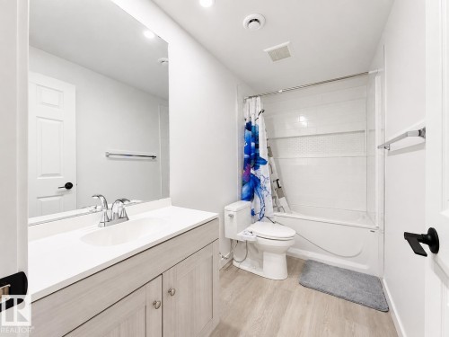 White vanity with a single basin sink, chrome faucet, and wood-finish cabinetry - 3525 22 St Nw, Edmonton, AB 