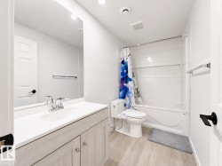 White vanity with a single basin sink, chrome faucet, and wood-finish cabinetry - 