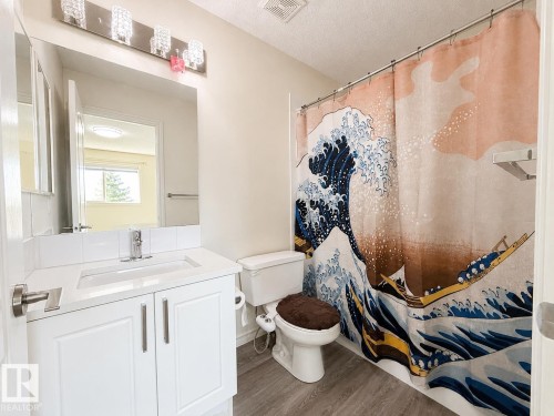 Vanity with white shaker-style cabinetry, a chrome faucet, and a large wall-mounted mirror - 3525 22 St Nw, Edmonton, AB 