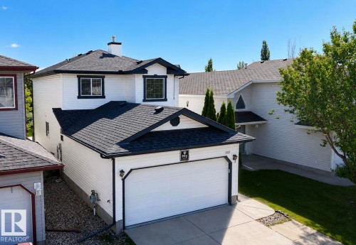 Two-story residence featuring white siding, black trim, and a prominent attached garage with a white door - 3525 22 St Nw, Edmonton, AB 