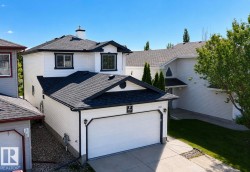 Two-story residence featuring white siding, black trim, and a prominent attached garage with a white door - 