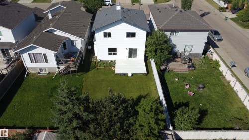 Expansive backyard featuring a large green lawn, mature trees, and a wooden fence - 3525 22 St Nw, Edmonton, AB 