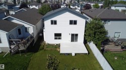 Expansive backyard featuring a manicured lawn, a large deck, and a privacy fence - 