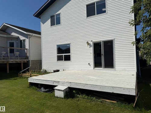 Rear exterior with horizontal vinyl siding, sliding glass patio door, and a ground-level deck - 3525 22 St Nw, Edmonton, AB 