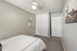 Bright secondary bedroom featuring neutral wall finishes, carpeted flooring, a ceiling-mounted light fixture, and dual closets with white panel doors providing ample storage - 